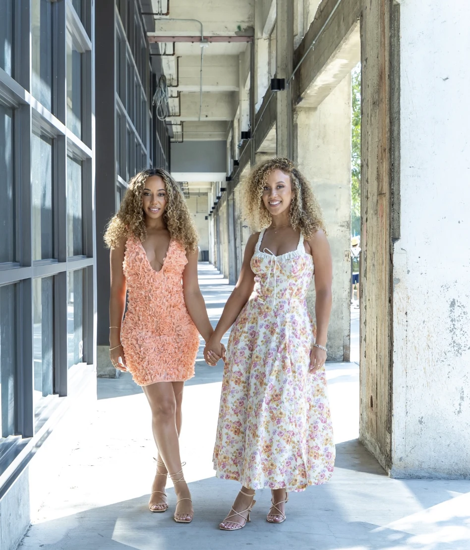 Krystle and Bethany Whitley holding hands in a sunlit corridor